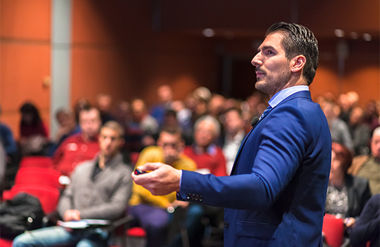 a man in a suit holding a remote in front of a crowd
