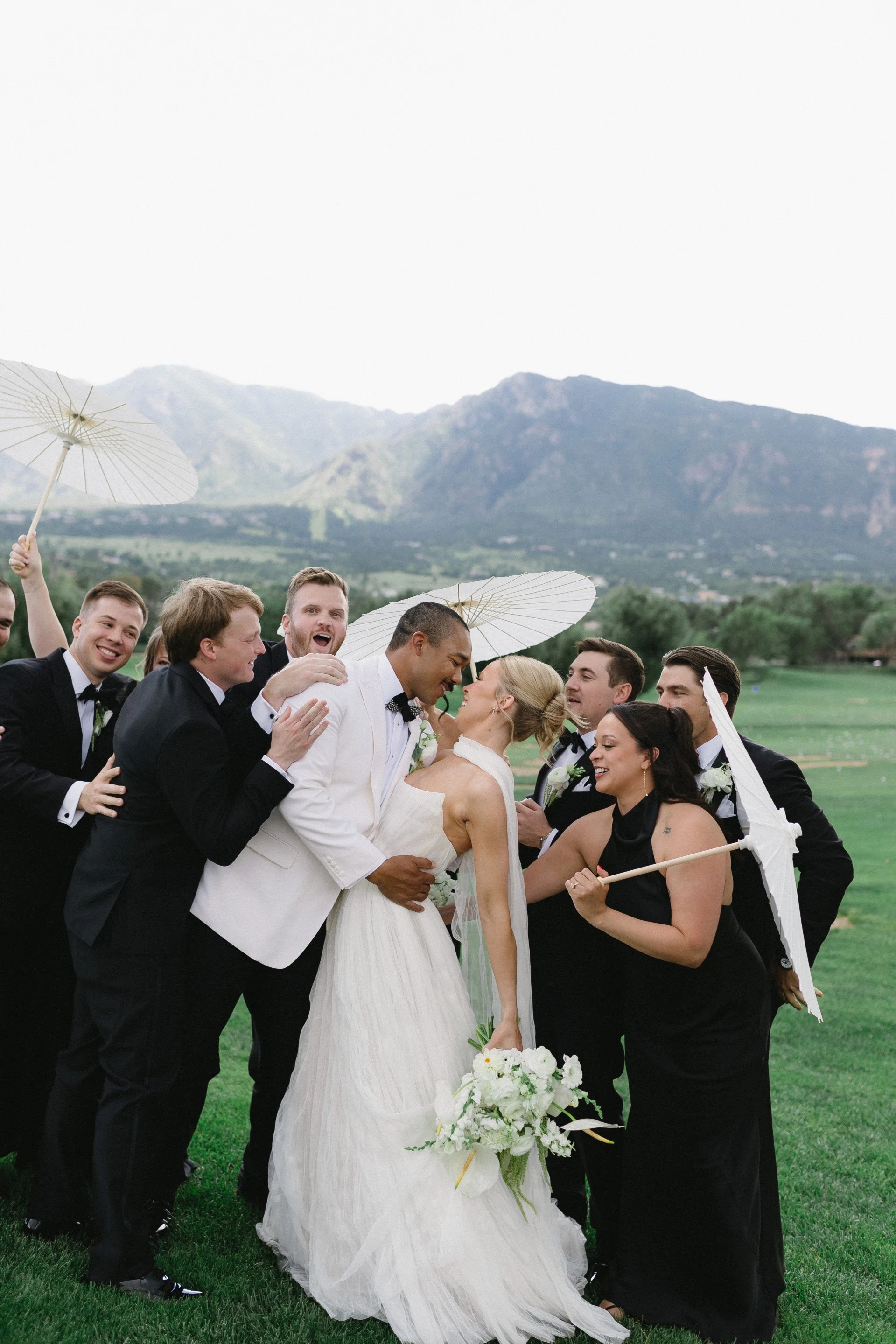 a group of people in suits and tuxedos kissing