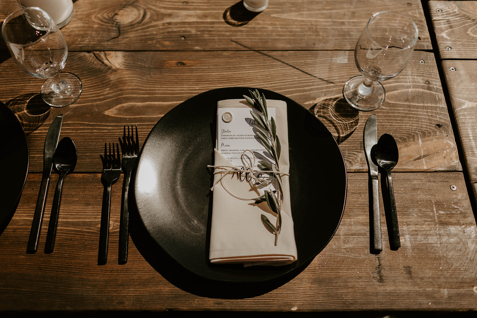a plate with a napkin, fork and knife on a wooden table