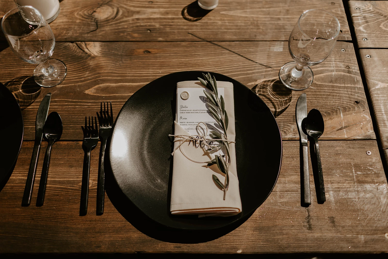 a plate with a napkin, fork and knife on a wooden table