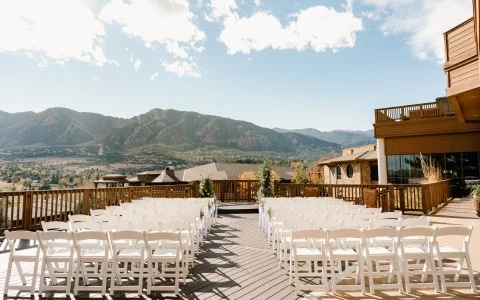 a group of white chairs on a deck with mountains in the background