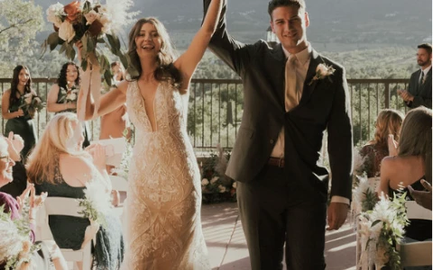 a man and woman holding hands and walking down a aisle