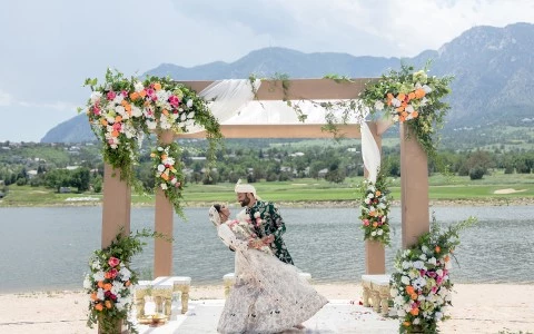 a man and woman in a wedding dress under a floral arch