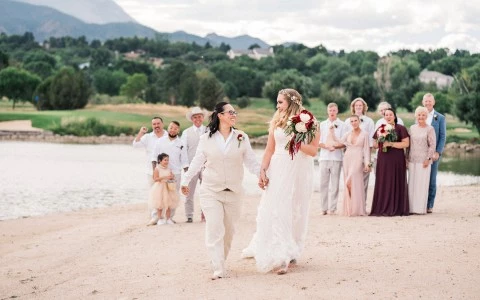 a bride and her partner walking on a beach