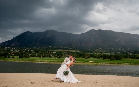a man and woman in wedding dress hugging with mountains in the back