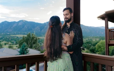 a man and woman standing on a porch looking at mountains