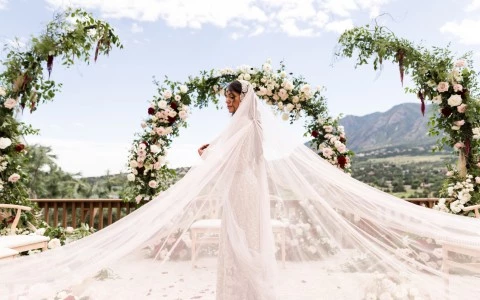 a woman in a white dress under a floral arch