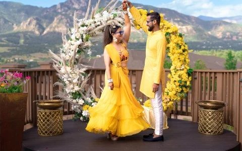 a man and woman in yellow dress standing on a deck with flowers