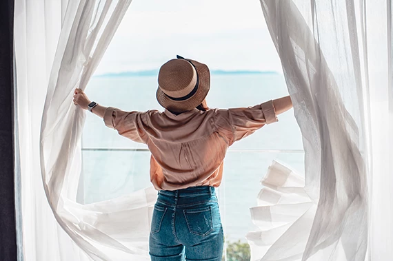a woman with a hat opening a window