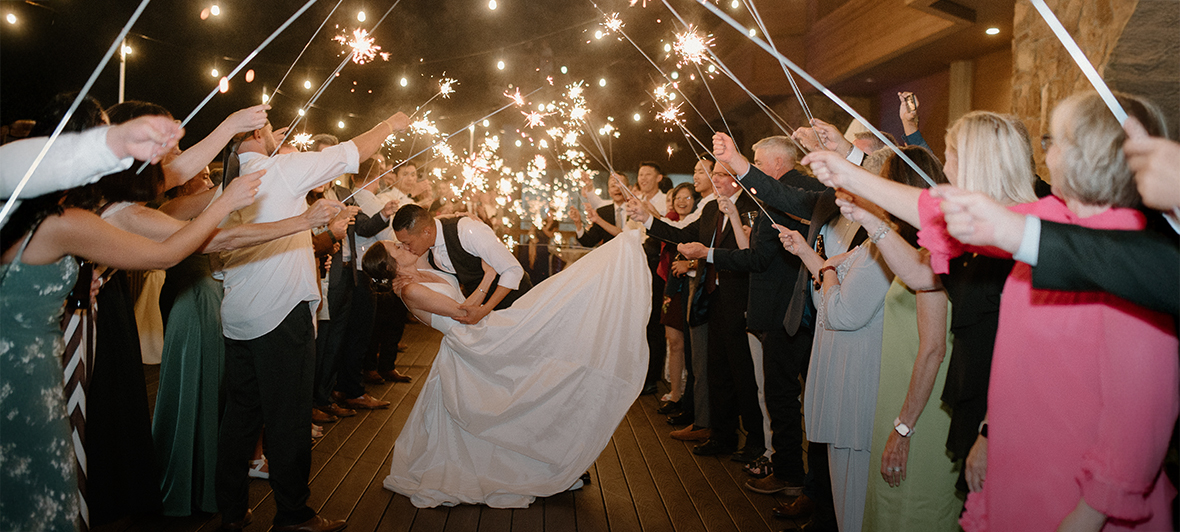 a bride and groom kissing in front of a crowd of people holding sparklers