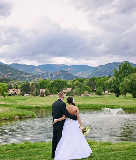 a man and woman in a wedding dress by a lake