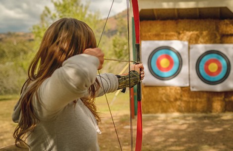 a woman aiming a bow and arrow