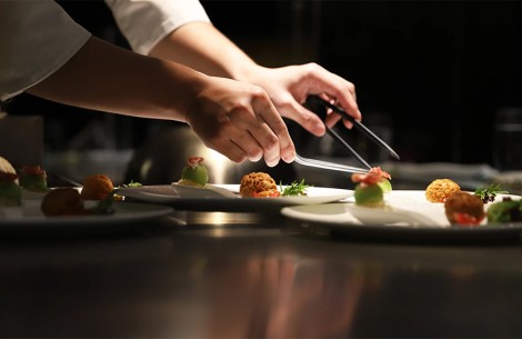 a person's hands holding tongs to a plate of food