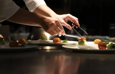 a person's hands holding tongs to a plate of food