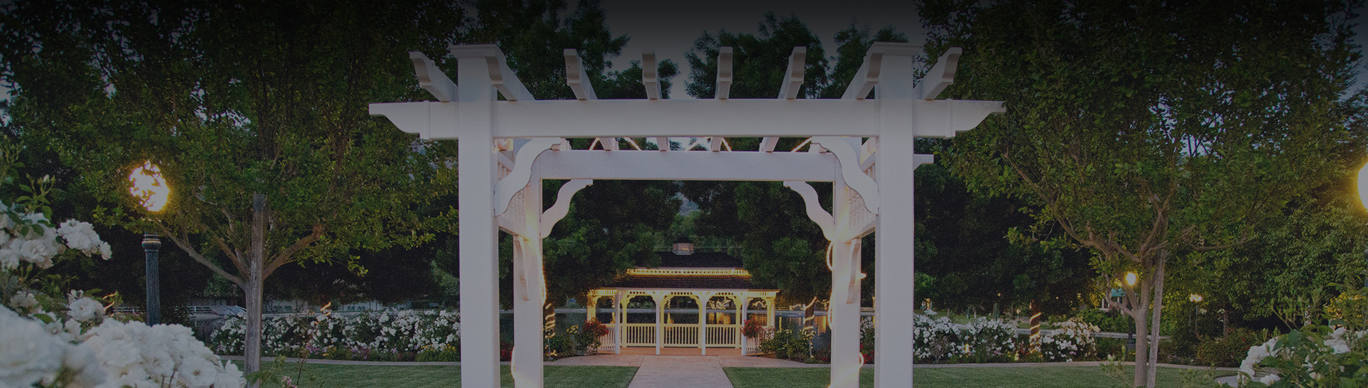 a white arbor with a gazebo and a walkway