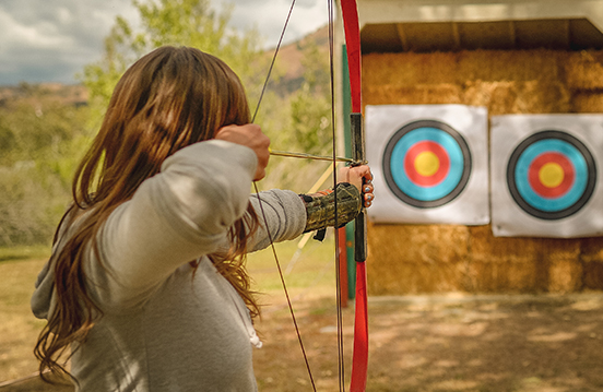 a woman aiming a bow and arrow
