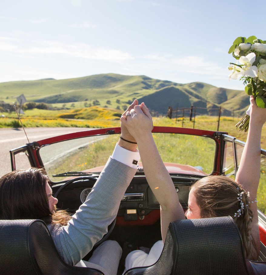 a couple in a convertible holding flowers