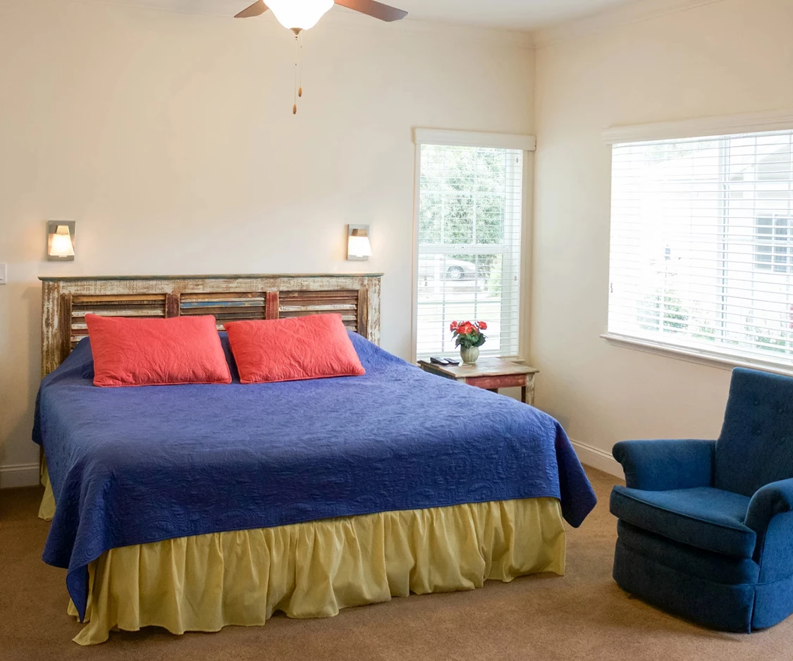 a bedroom with a blue and red bed and a blue chair
